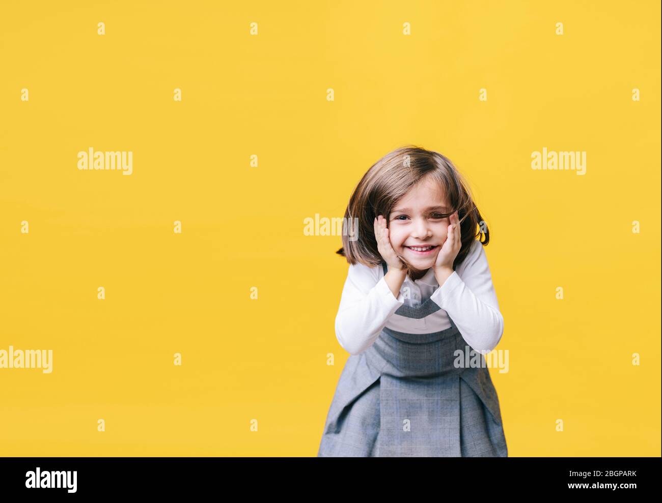 A happy little girl laughing surprised with her hands on her face in ...