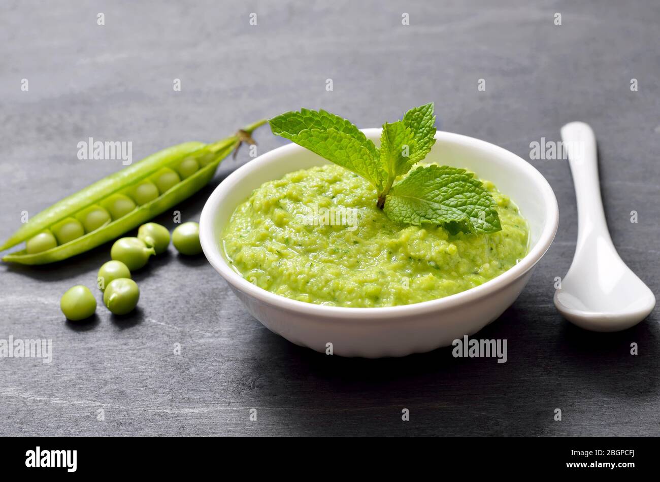 Homemade green pea puree in white bowl. Vegetarian food Stock Photo