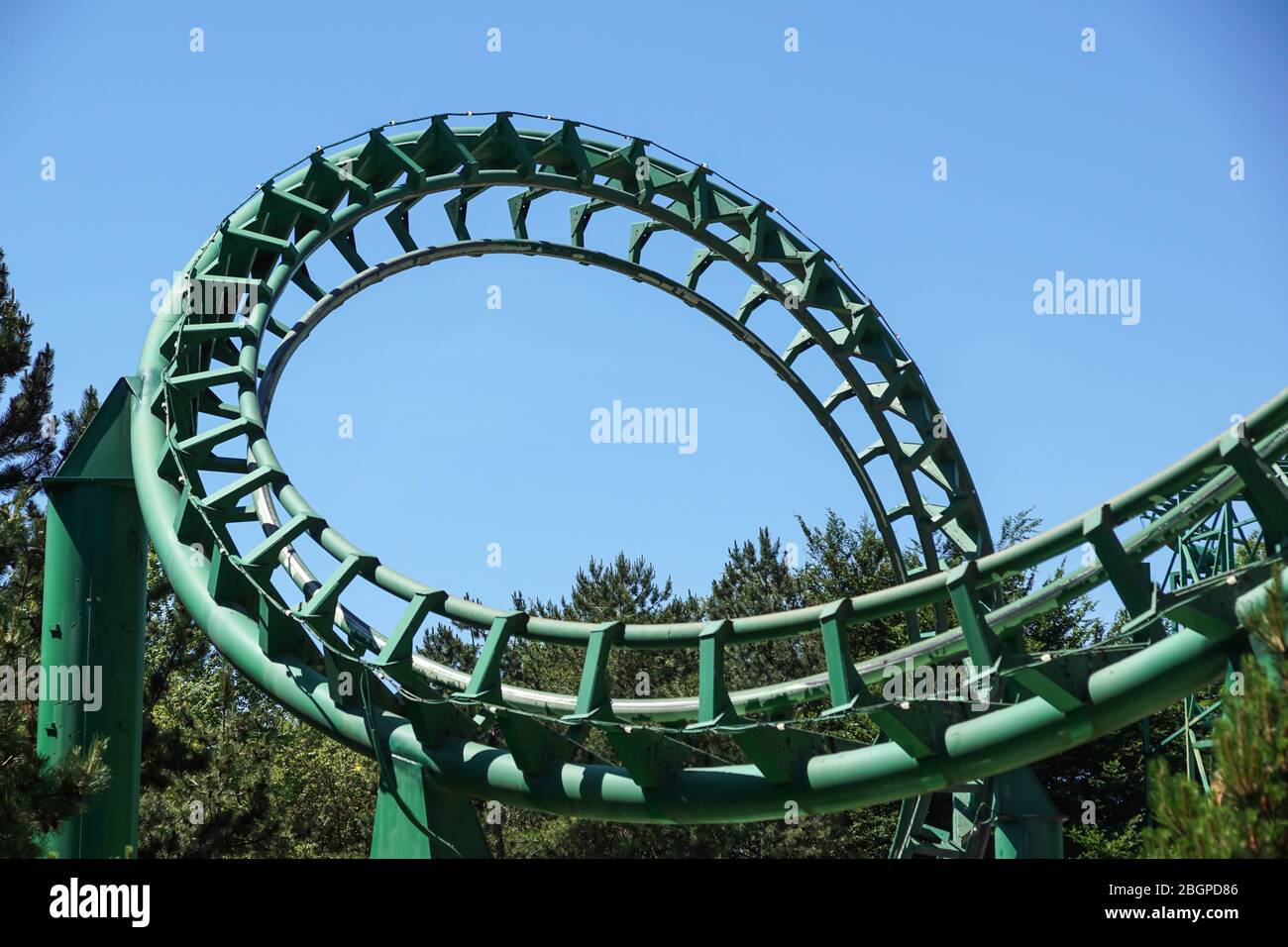 Loop and turn on a green roller coaster in an amusement park Stock Photo