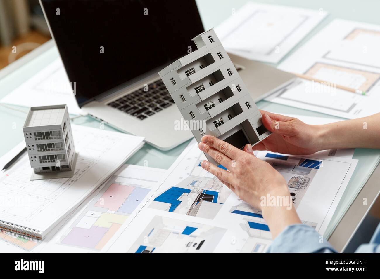 Close up of a house model in architect's  hands in a construction bureau. Architectural and construction bureau working concept Stock Photo
