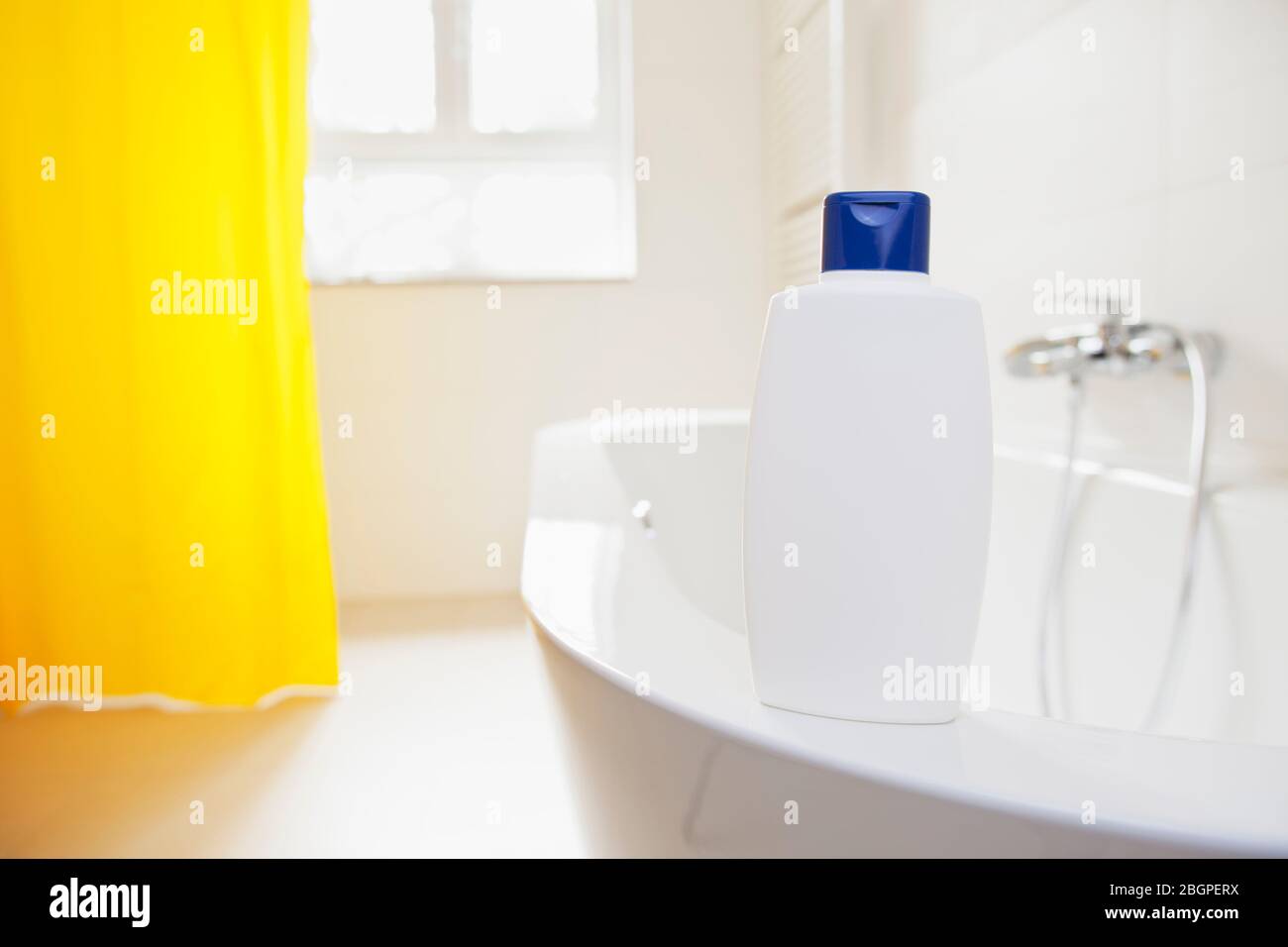 Shower gel, shampoo or soap standing on a bathtub in a brigh bathroom - focus on the shampoo in the foreground with copyspace Stock Photo