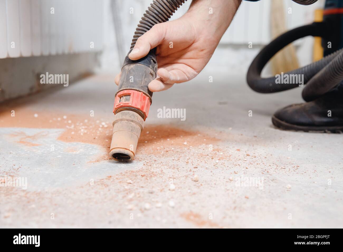 Worker vacuuming debris and dust from floor after drilling concrete