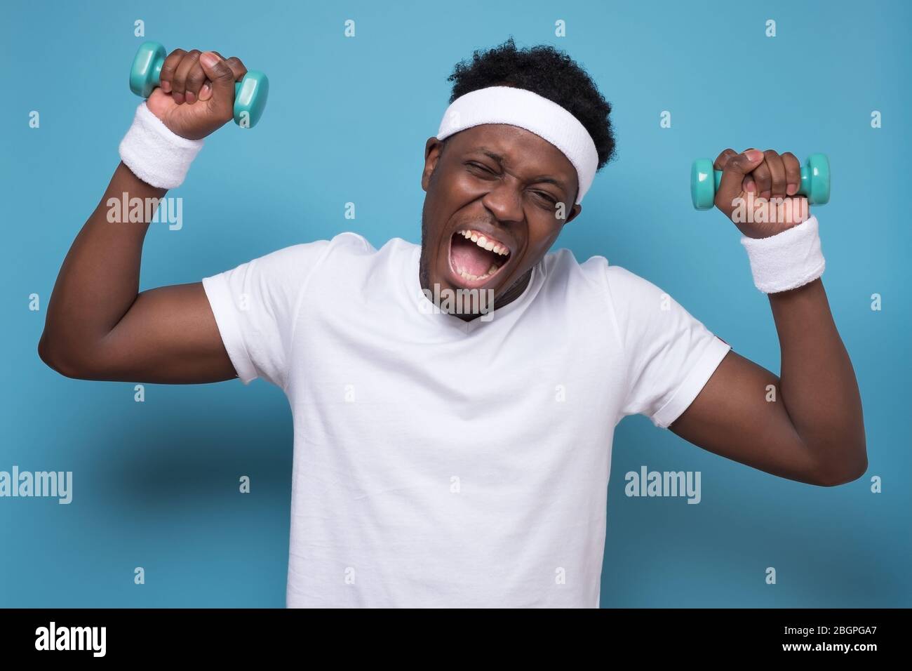 Smiling young african american guy training with dumbbells. Stock Photo