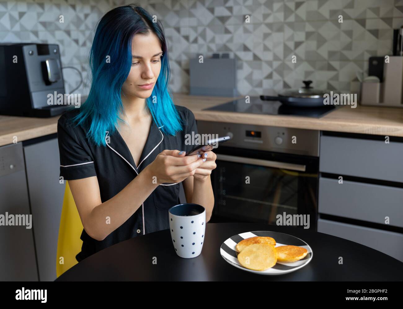 Beautiful young hipster woman taking photo of her breakfast at modern kitchen Stock Photo