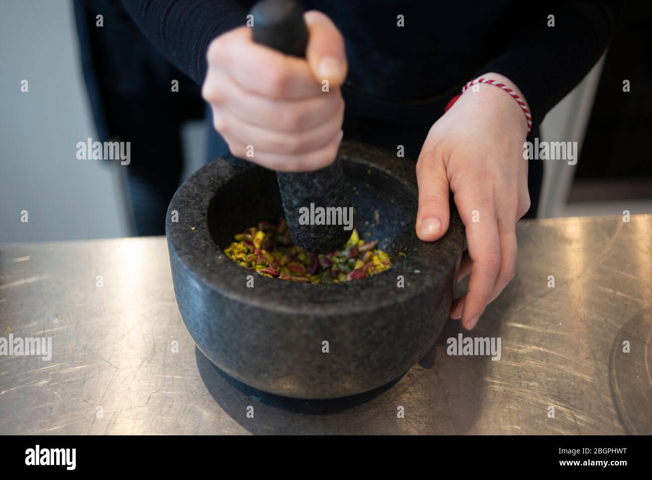 Chef uses stone pestel and mortar to crush pistachio nuts Stock Photo