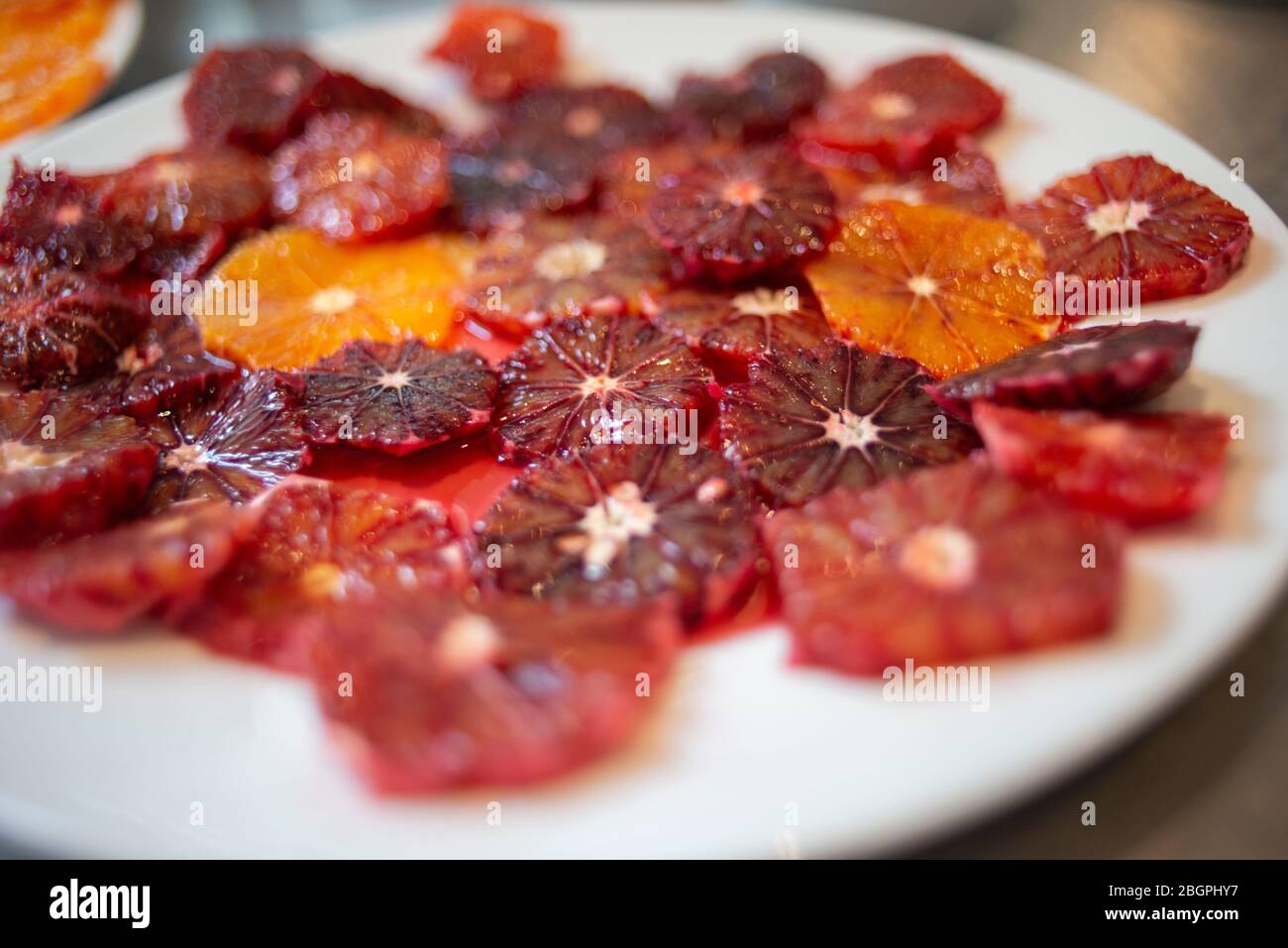 A large white plate covered in slices of blood oranges Stock Photo