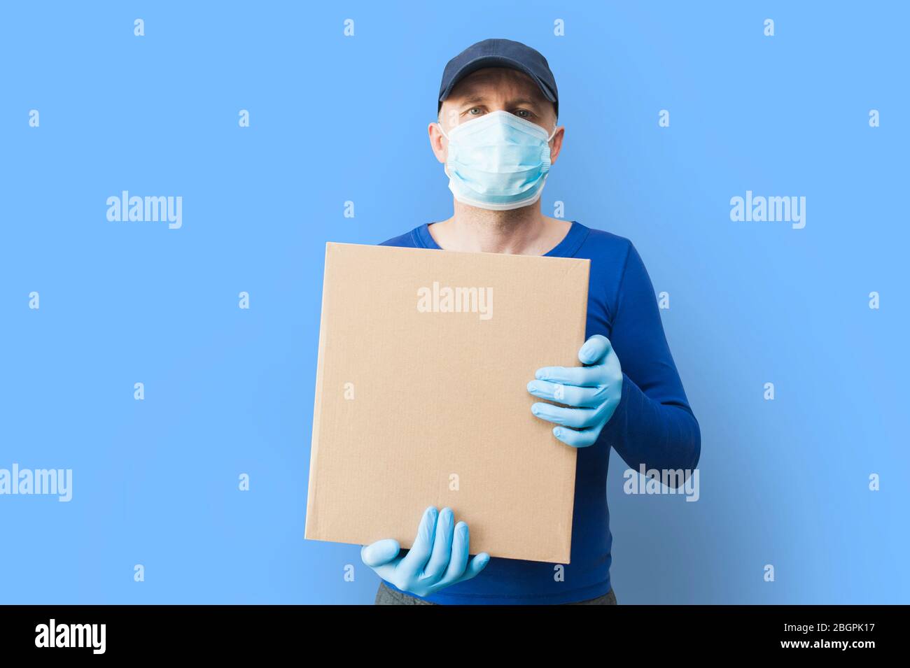 Delivery man holding cardboard boxes in medical rubber gloves and mask. copy space. Fast and free Delivery transport. Online shopping and Express Stock Photo