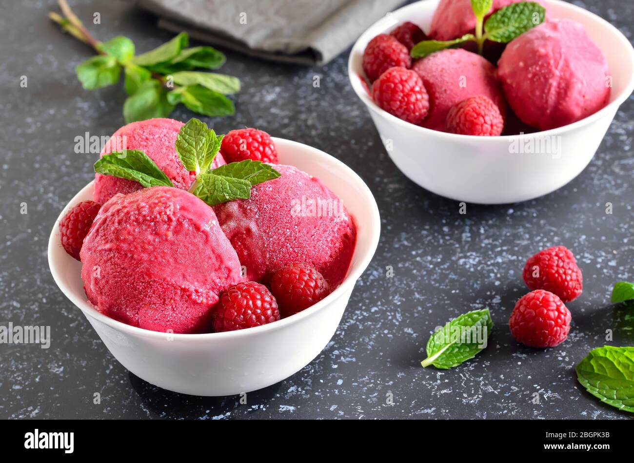 Raspberry ice cream scoop with fresh raspberries in bowl on stone background, close up view Stock Photo