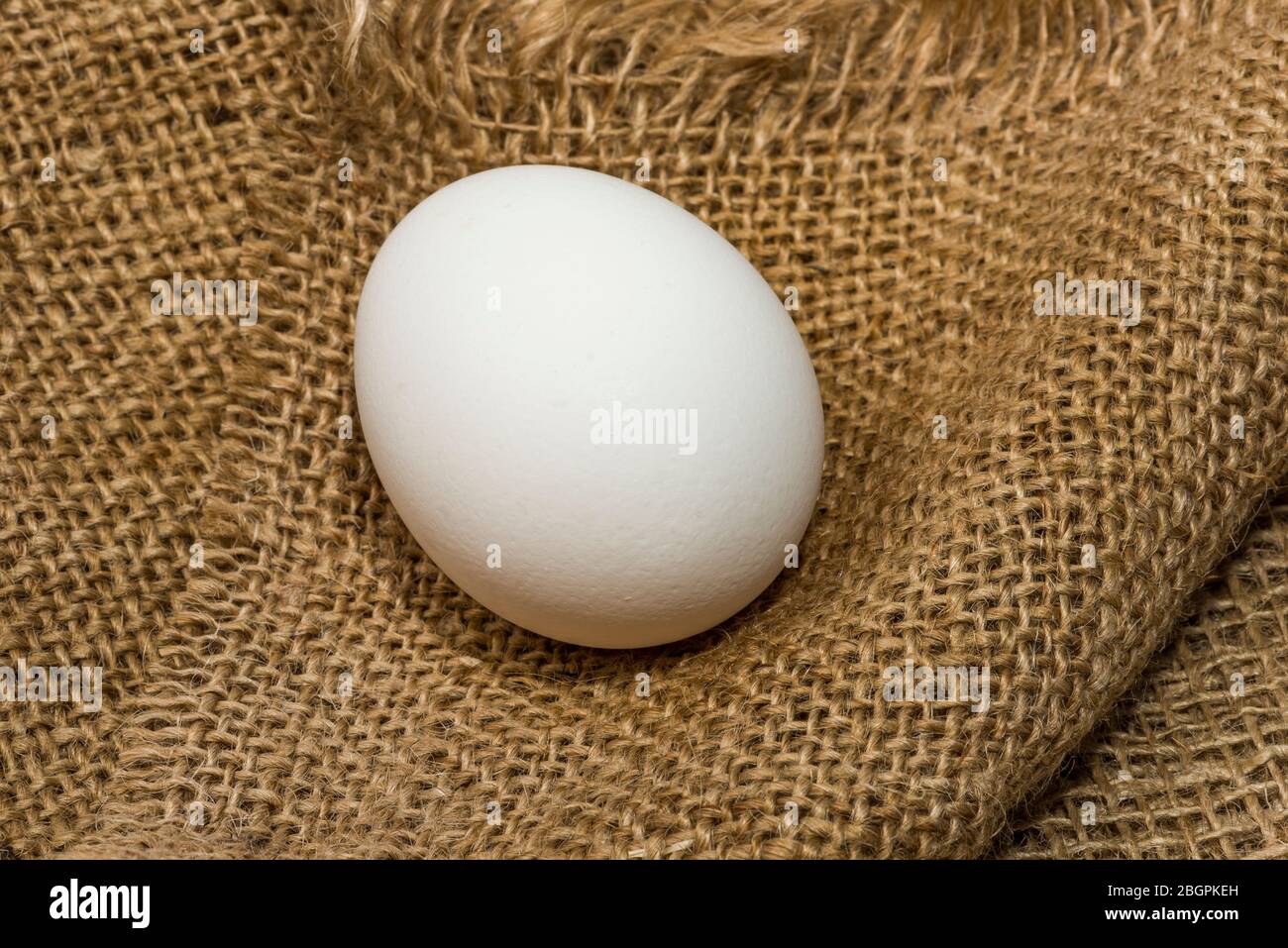 White chicken eggs wrapped in burlap next to a basket on a White eggs ...