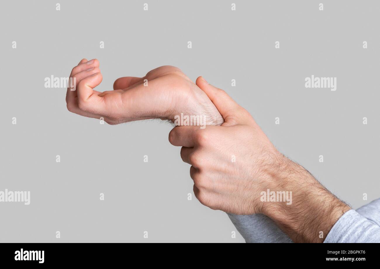Wrist pain. Man massages joint in his hand Stock Photo Alamy