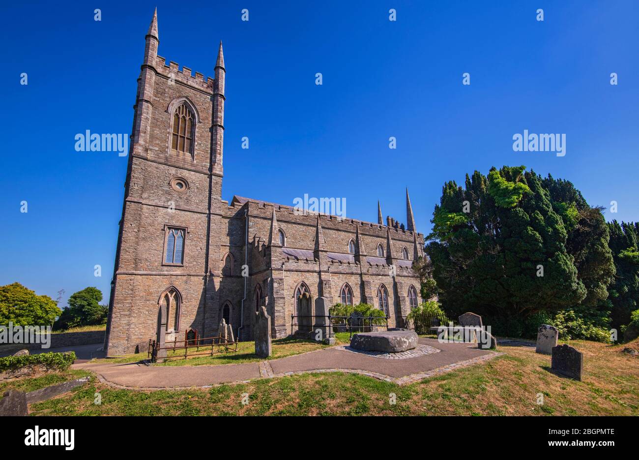 Ireland, County Down, Downpatrick, Cathedral Church of the Holy Trinity also known as Down Cathedral with Mourne granite slab marking the traditional burial place of St Patrick in the foreground. Stock Photo