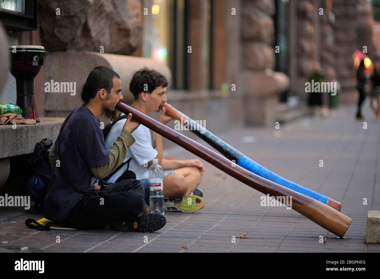 Two boys, street musicians, playing didgeridoo, wind instruments of