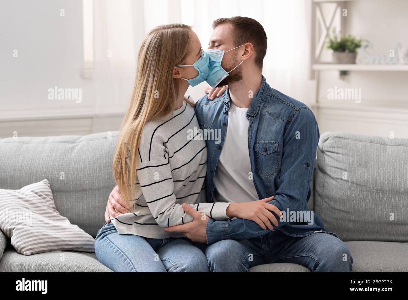 Young married couple kissing in protective medical masks Stock Photo ...