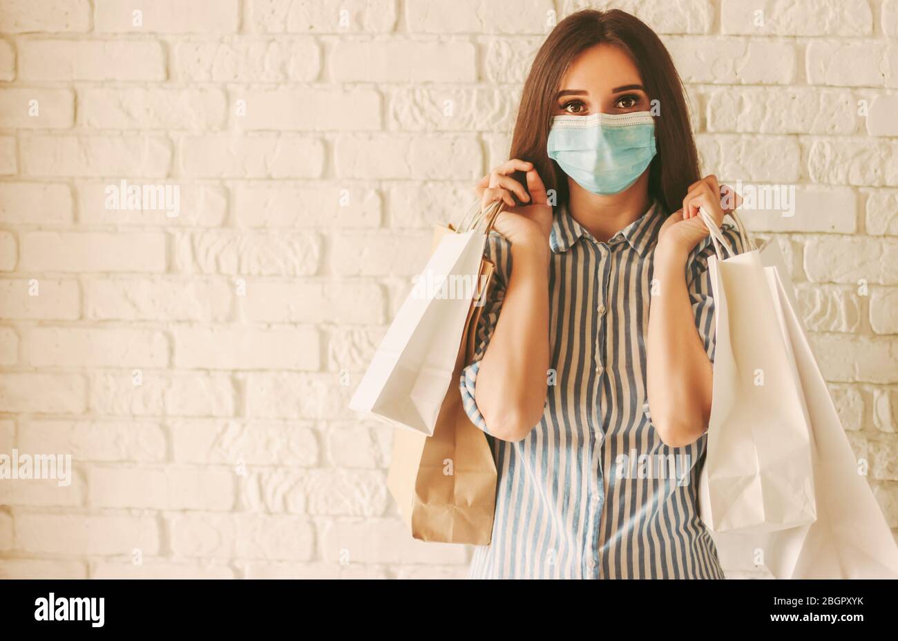 Happy girl shopper in protective face mask with paper bags in hands. Young  woman in medical face mask holding shopping bags. Girl shopaholic in mall  Stock Photo - Alamy