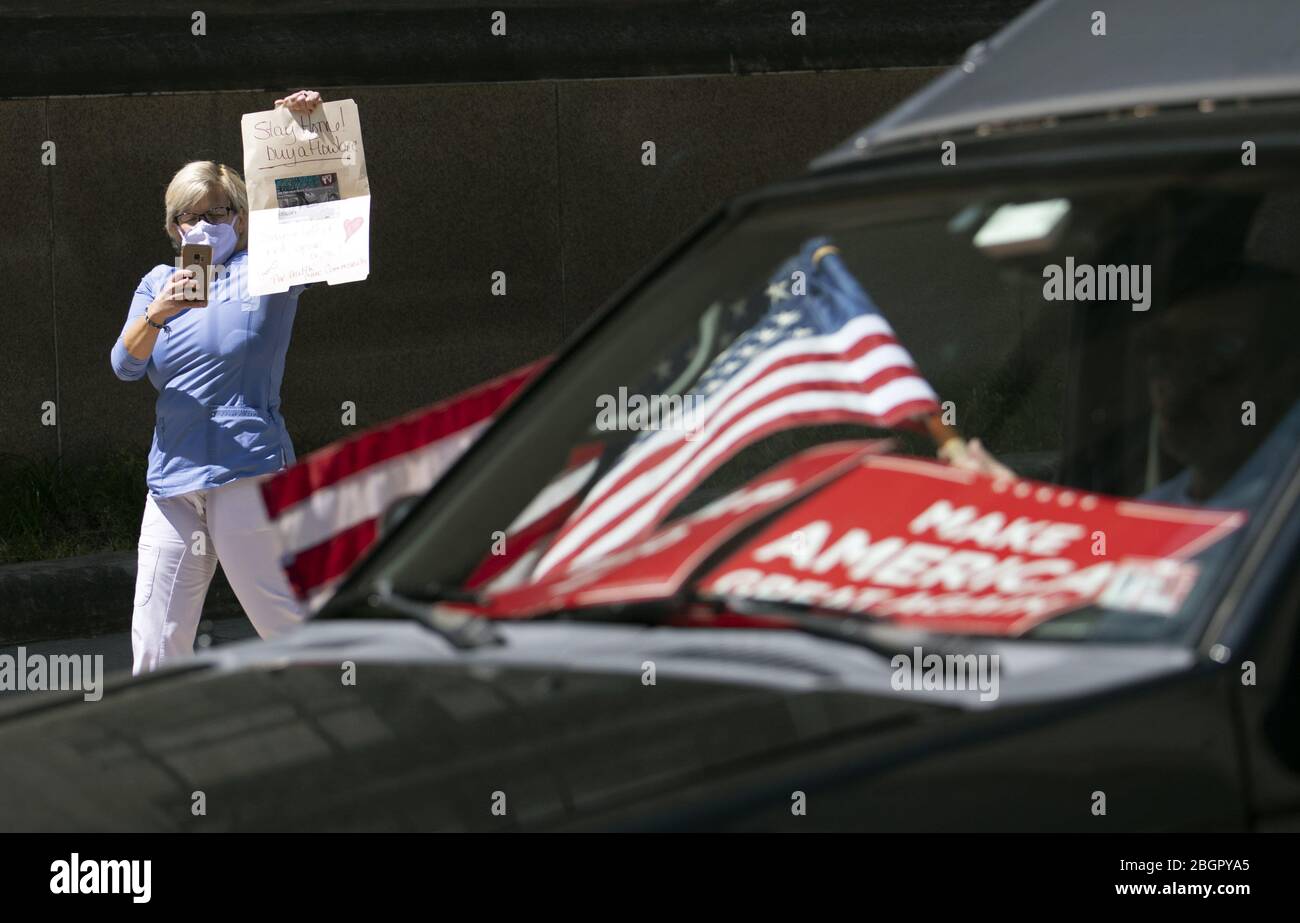Richmond, United States. 22nd Apr, 2020. A self-identified member of the medical community holds a counter protest as demonstrators protest from the vehicles as they call on Gov. Ralph Northam to 'reopen Virginia' and end executive order 53 with bans gatherings of over 10 in the midst of the Coronavirus COVID-19 pandemic, near the State Capitol Building in Richmond, Virginia on Wednesday, April 22, 2020. The group is urging the reopening of business despite the COVID-19 pandemic still infecting the nation. Photo by Kevin Dietsch/UPI Credit: UPI/Alamy Live News Stock Photo