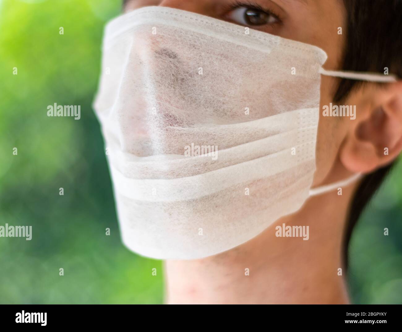 Man wearing face surgical medical white mask closeup Stock Photo