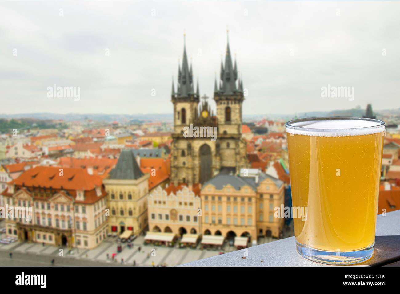 View of glass of light beer with background of the Old Town Square and