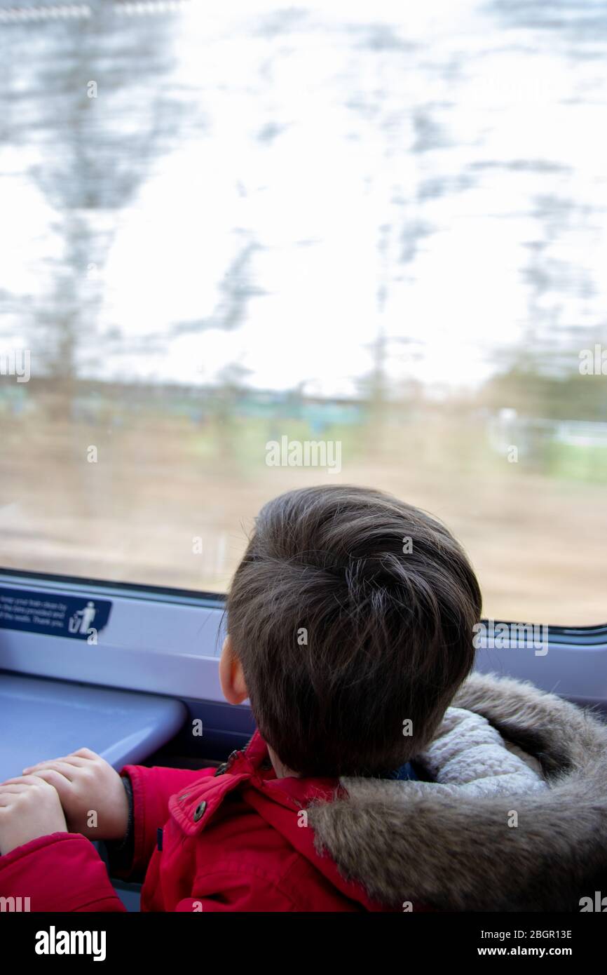 A small boy looking at the window on a moving train on a train journey Stock Photo