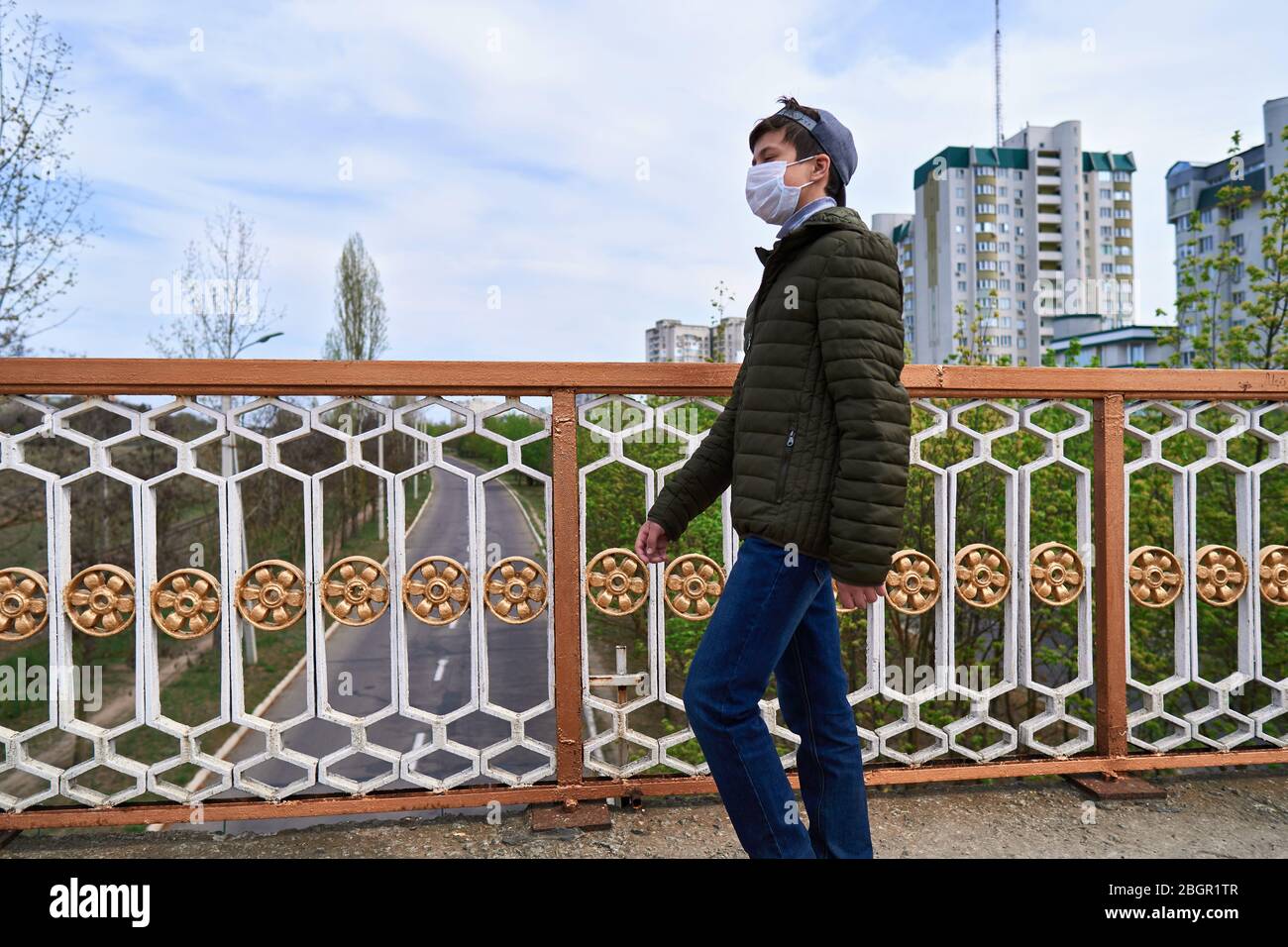 View of teen boy walks down the street during the day, a pedestrian walkway and ...