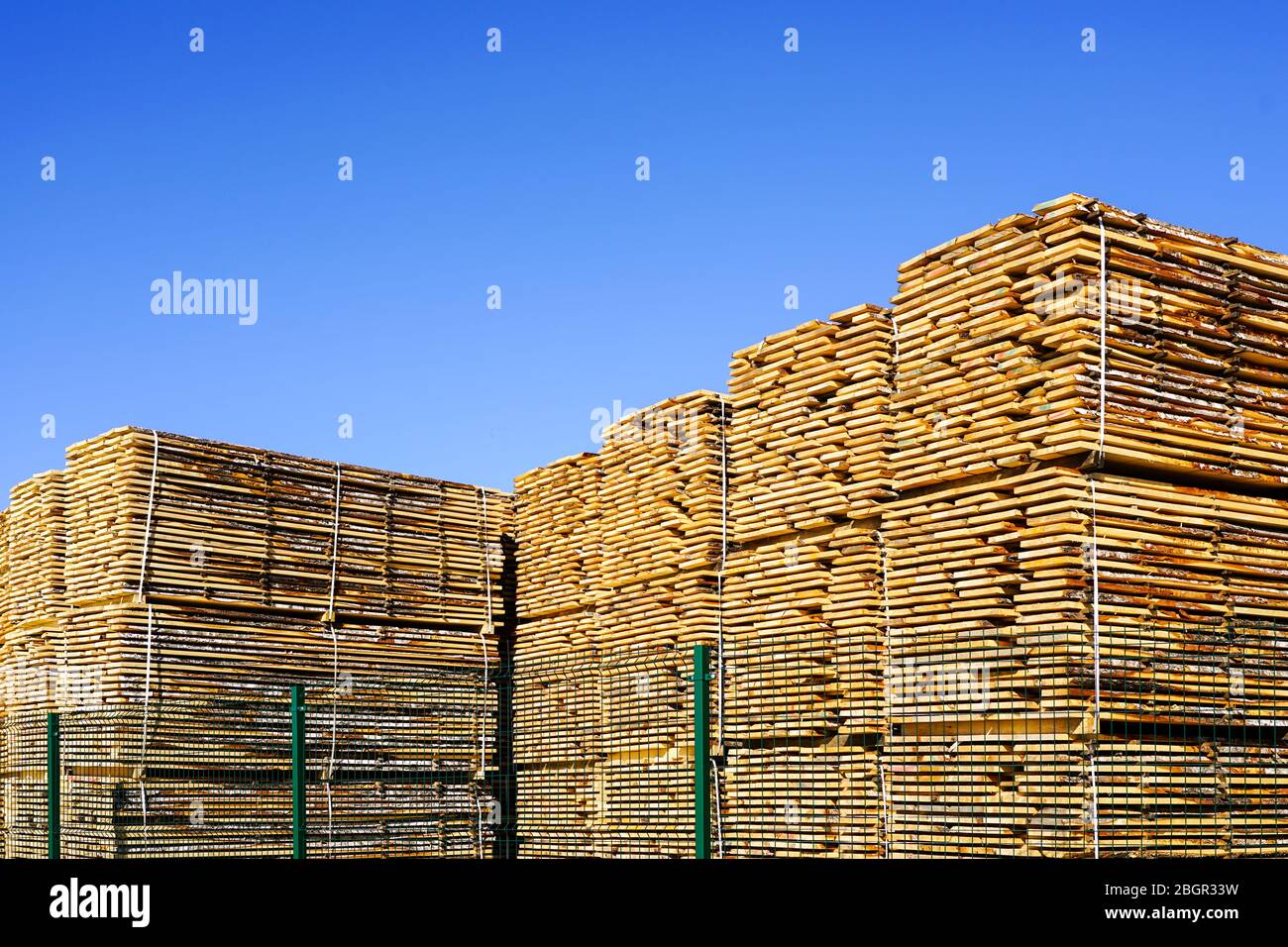 large stacks of wooden planks at the sawmill yard on the blue sky
