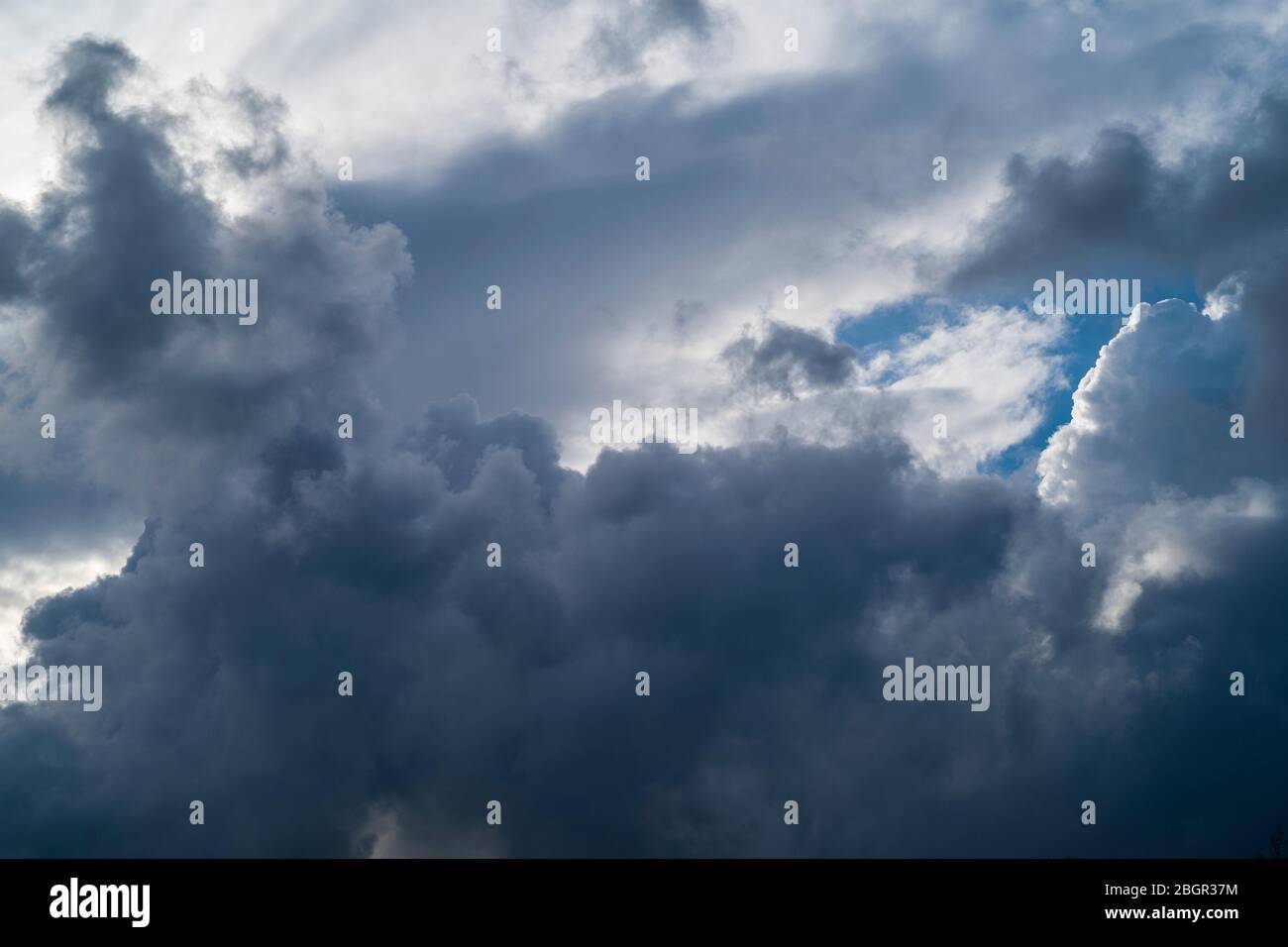 Cumulonimbus dark stormy puffy clouds in the sky and small patch of blue in skies above Gloucestershire, UK Stock Photo