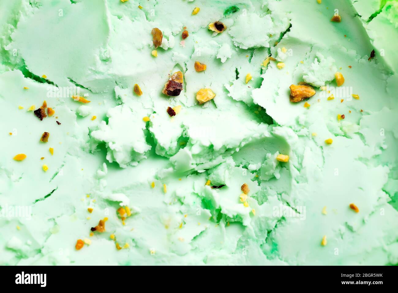 Close-up view of natural food background from homemade freshly cooked cold pistachio pastel green colored ice-cream dessert with ground-up nuts. Top v Stock Photo