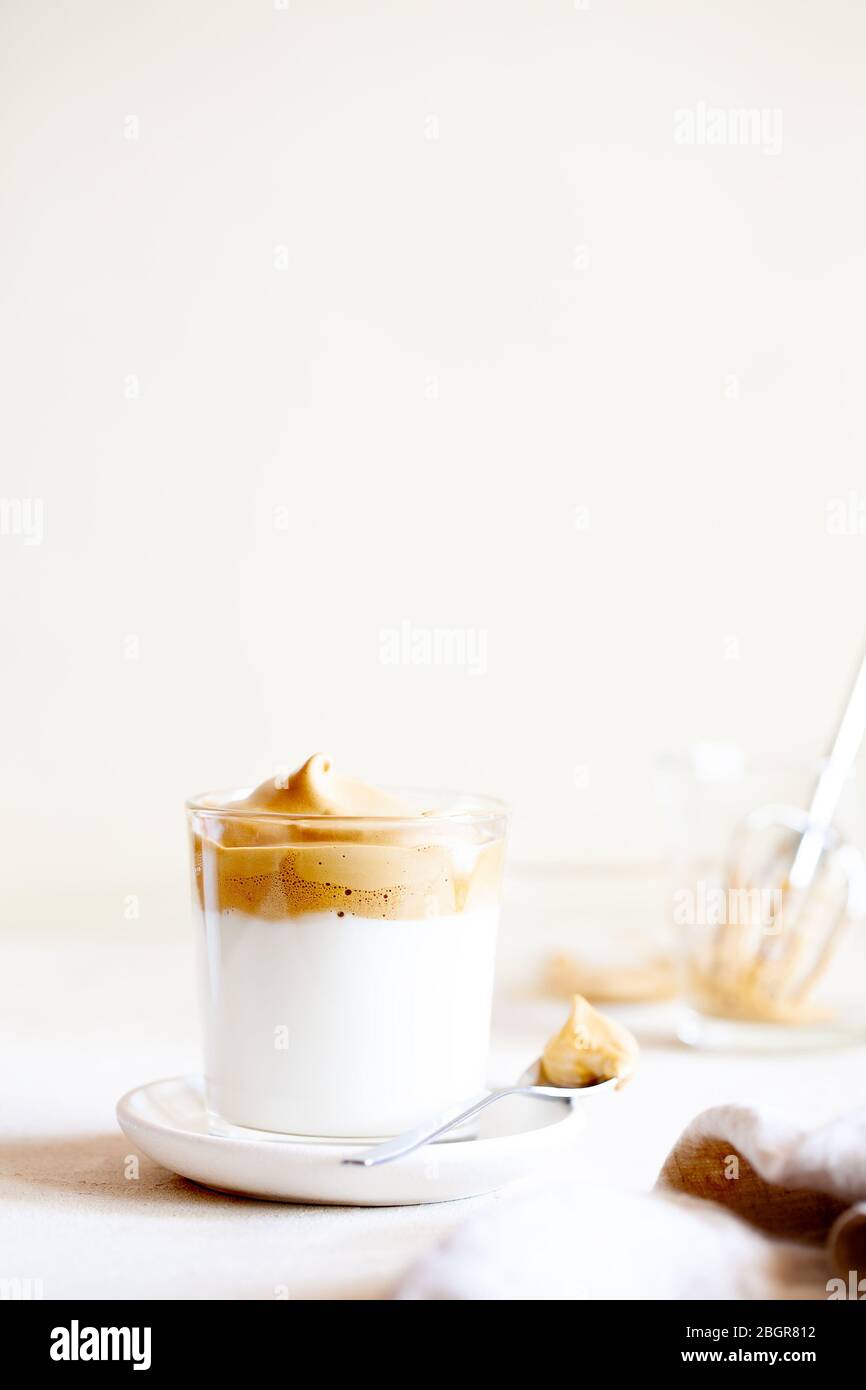 Trendy fluffy creamy whipped iced Dalgona coffee on white background.Korean drink latte espresso with foam of instant coffee.Vertical orientation Stock Photo