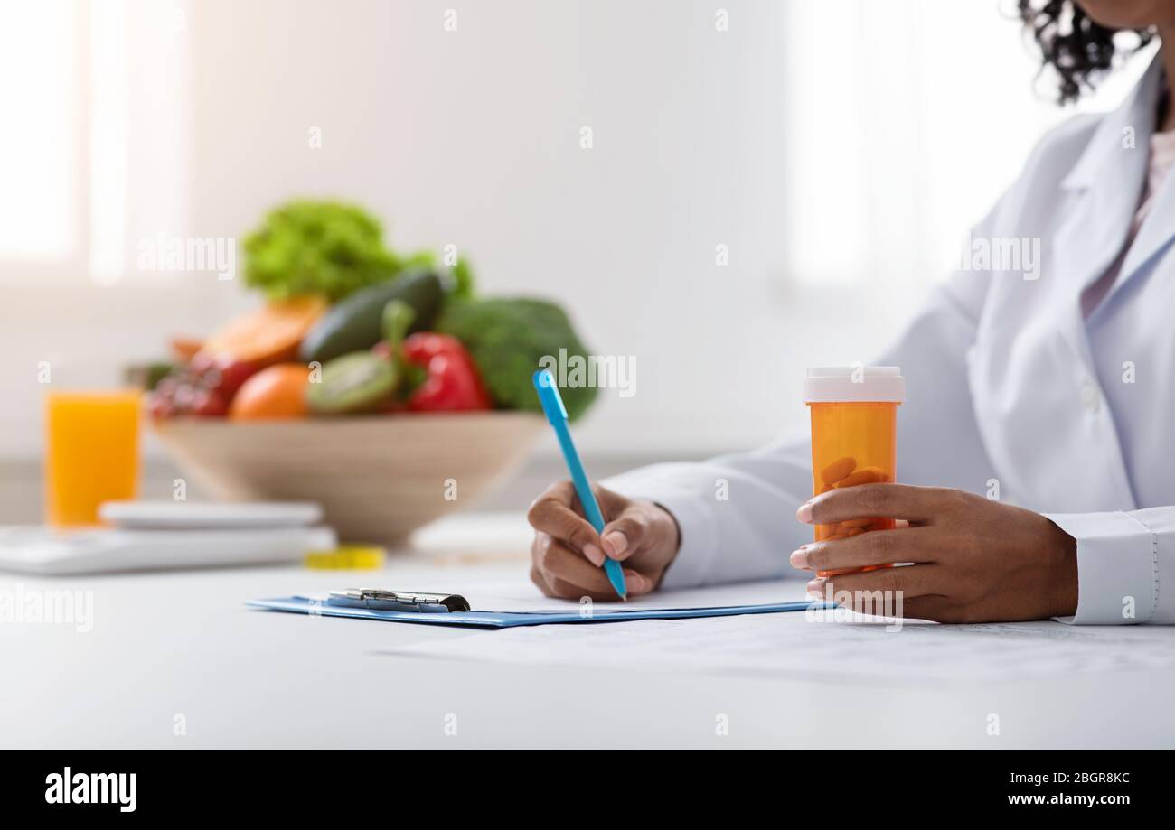 Cropped of black woman doctor dietologist prescribing pills Stock Photo