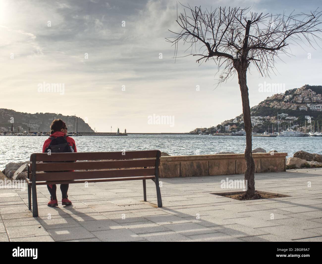 Dark heair woman traveler relax on bench on sea promenade. Stock Photo