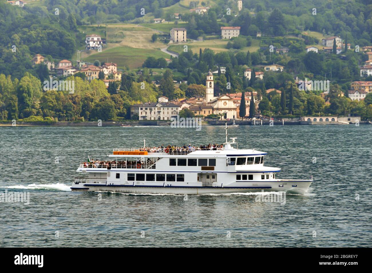 CADENABBIA, LAKE COMO - JUNE 2019: Small passenger ferry with people on board crossing Lake Como near Cadenabbia Stock Photo