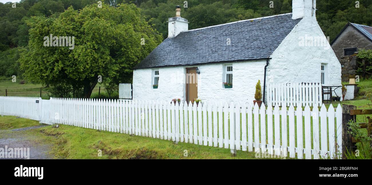 Quaint traditional whitewashed cottage with white paling fence and tiled roof in Appin, Argyll and Bute, Scotland Stock Photo