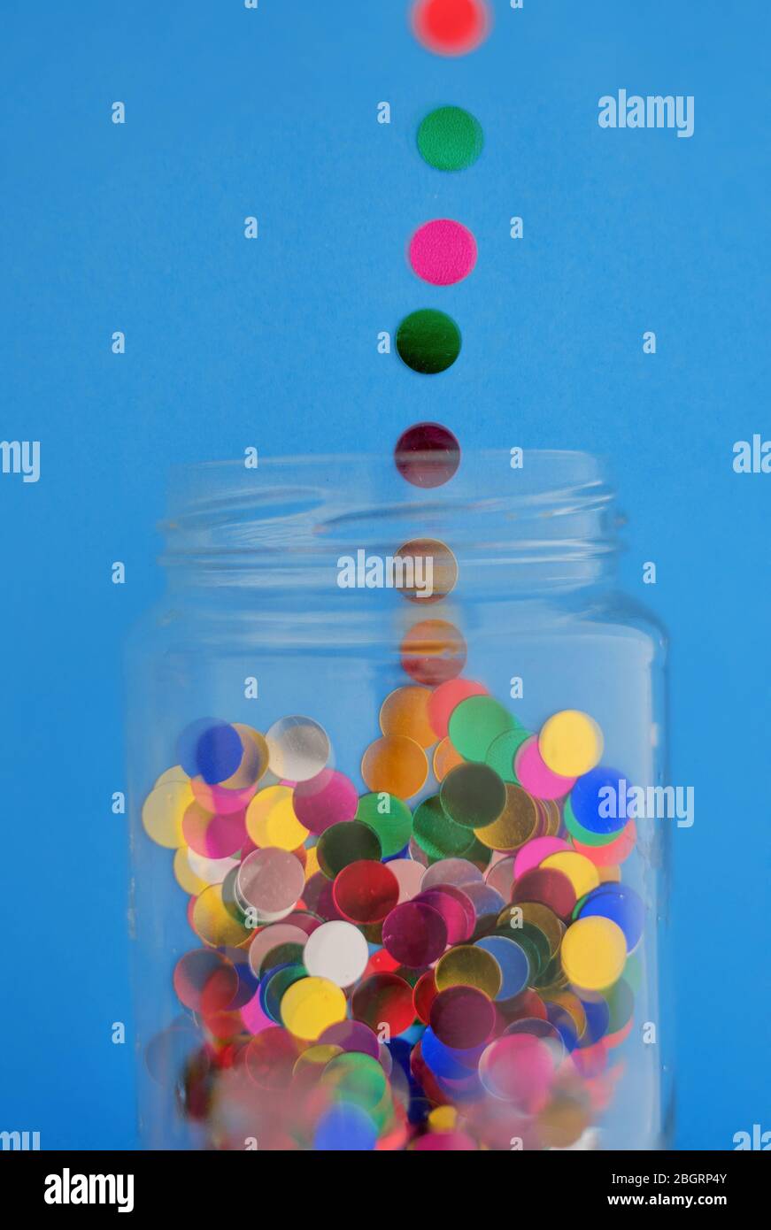 colorful confetti to being poured into a glass jar Stock Photo Alamy