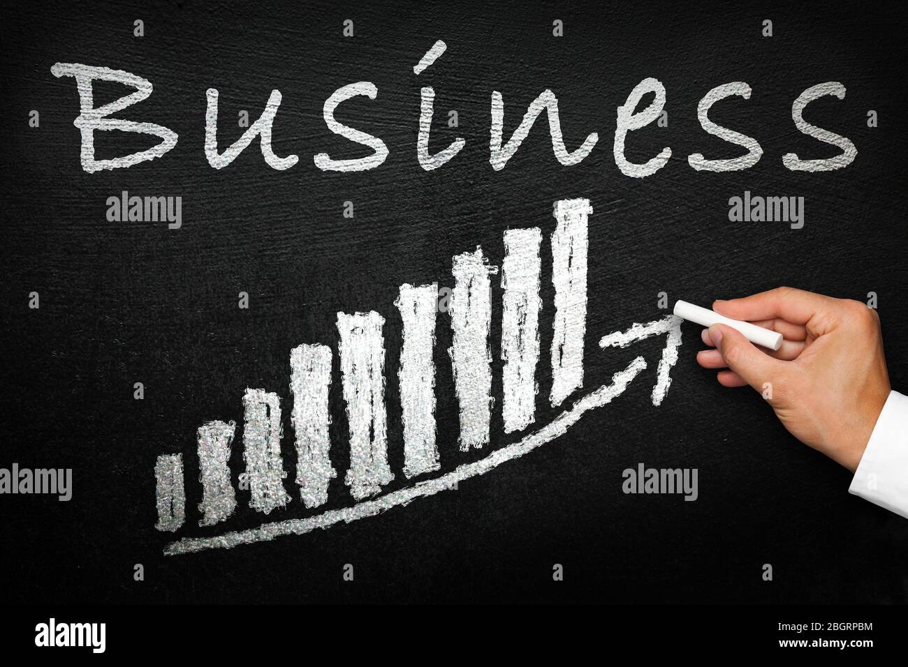 Blackboard with handwritten business text. Arrow going upwards and stack chart. Success and progress concept. Stock Photo