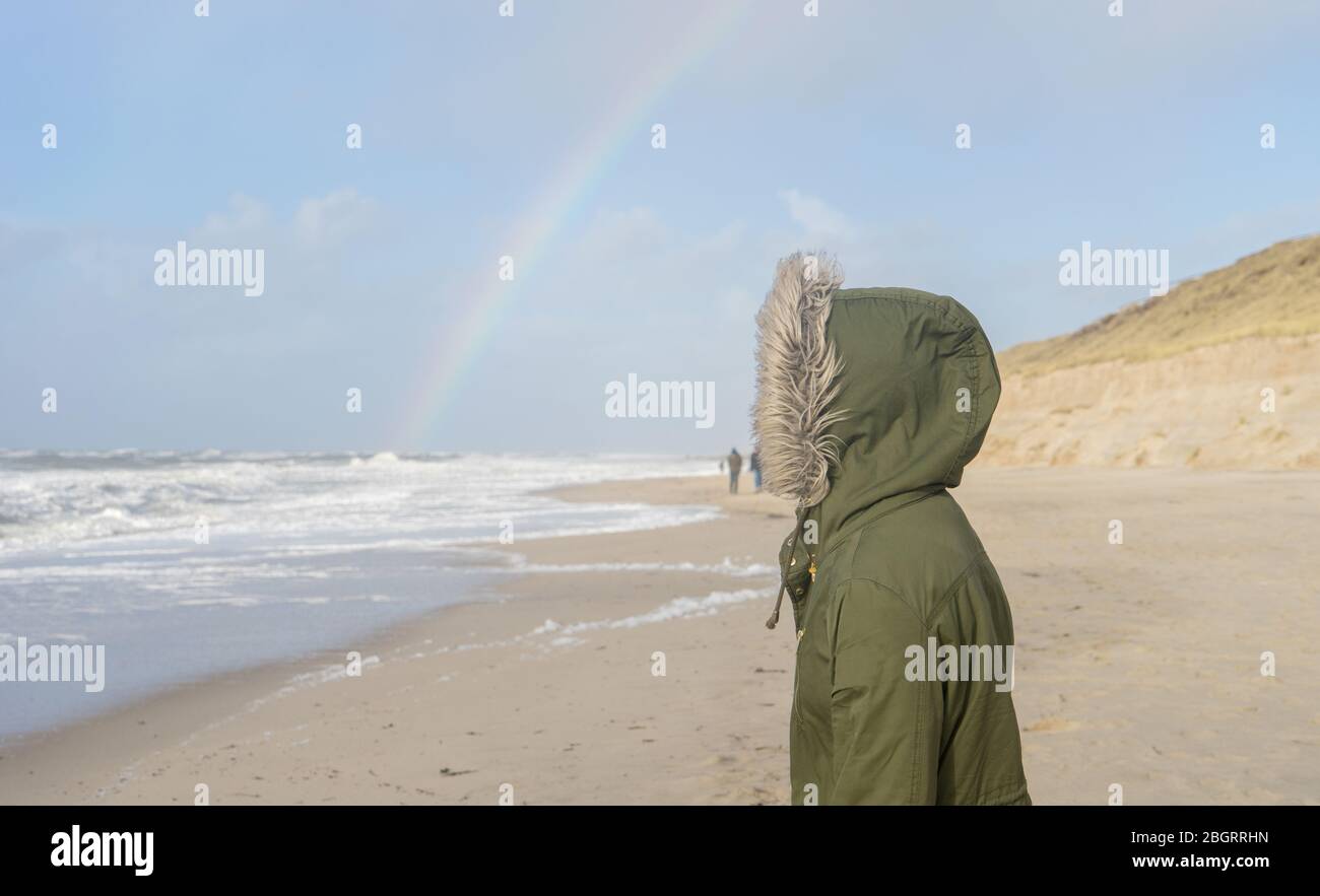 Unrecognizable person looks at the sea with a rainbow on the horizon Stock Photo