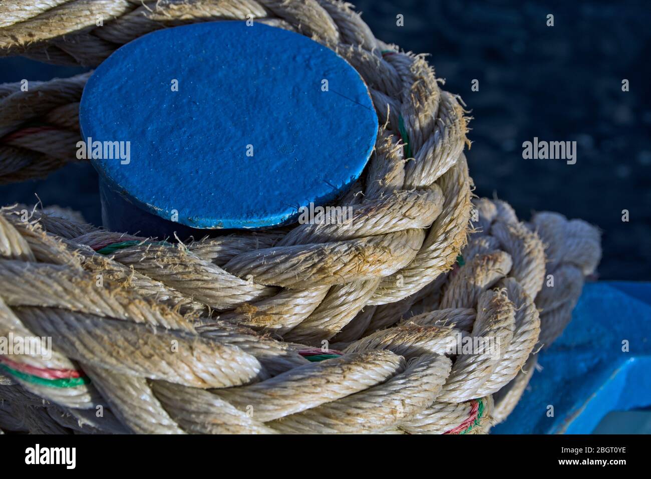 The rope that tied the boat to the blue metal pole on the shore at the marina. Stock Photo