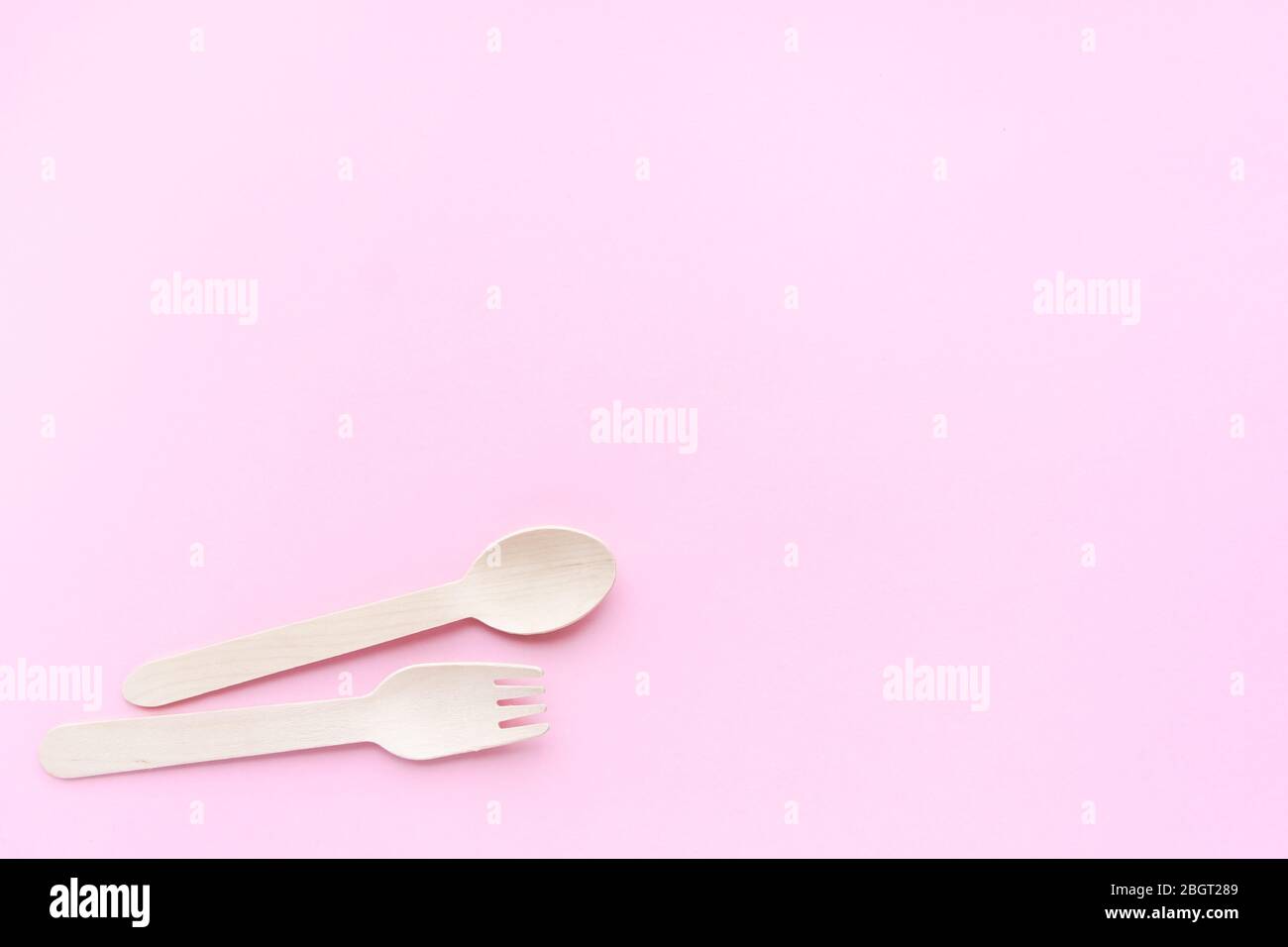 eco friendly disposable kitchenware utensils on pink background. wooden forks and spoons. ecology, zero waste concept. top view. flat lay. copyspace Stock Photo