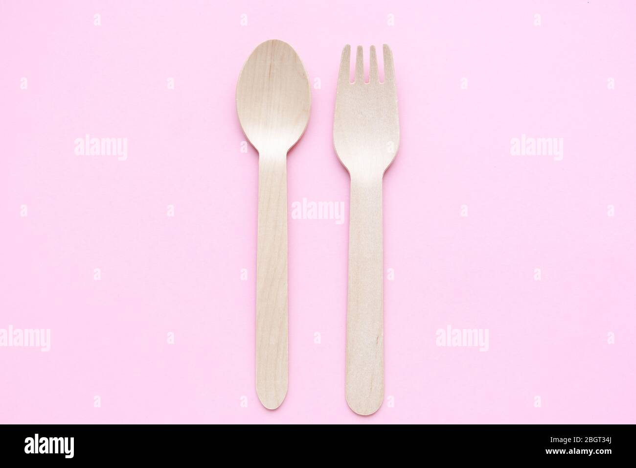 eco friendly disposable kitchenware utensils on pink background. wooden forks and spoons. ecology, zero waste concept. top view. flat lay Stock Photo