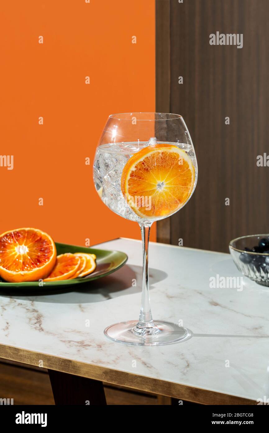 Gin tonic cocktail, garnished with orange slice, colorful background