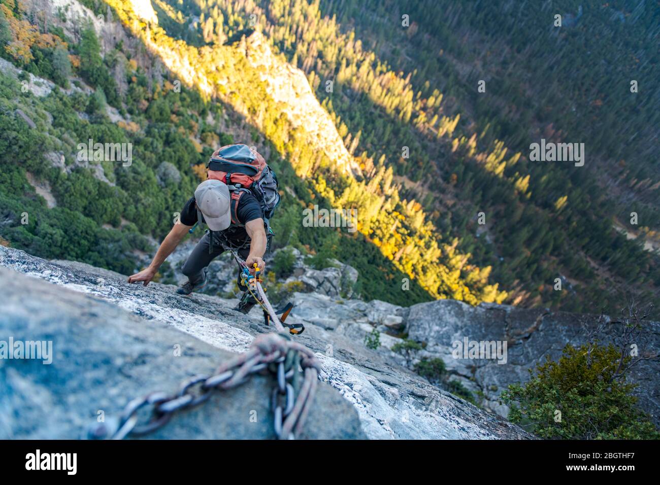 Man with hat looking down jugging rope up with backpack on El Capitan Stock Photo