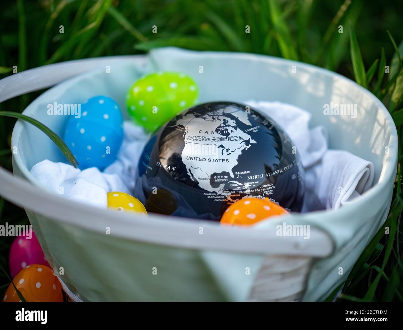 Earth globe sitting in an Easter basket full of polka dotted eggs. USA map in an Easter basket. Stock Photo