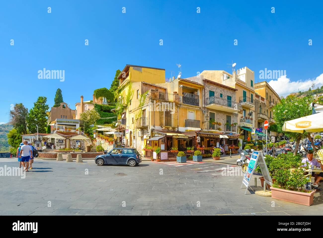 Busy corner with cafes and shops at the end of the main street, Corso Umberto, in the Sicilian city of Taormina Italy on a summer day Stock Photo