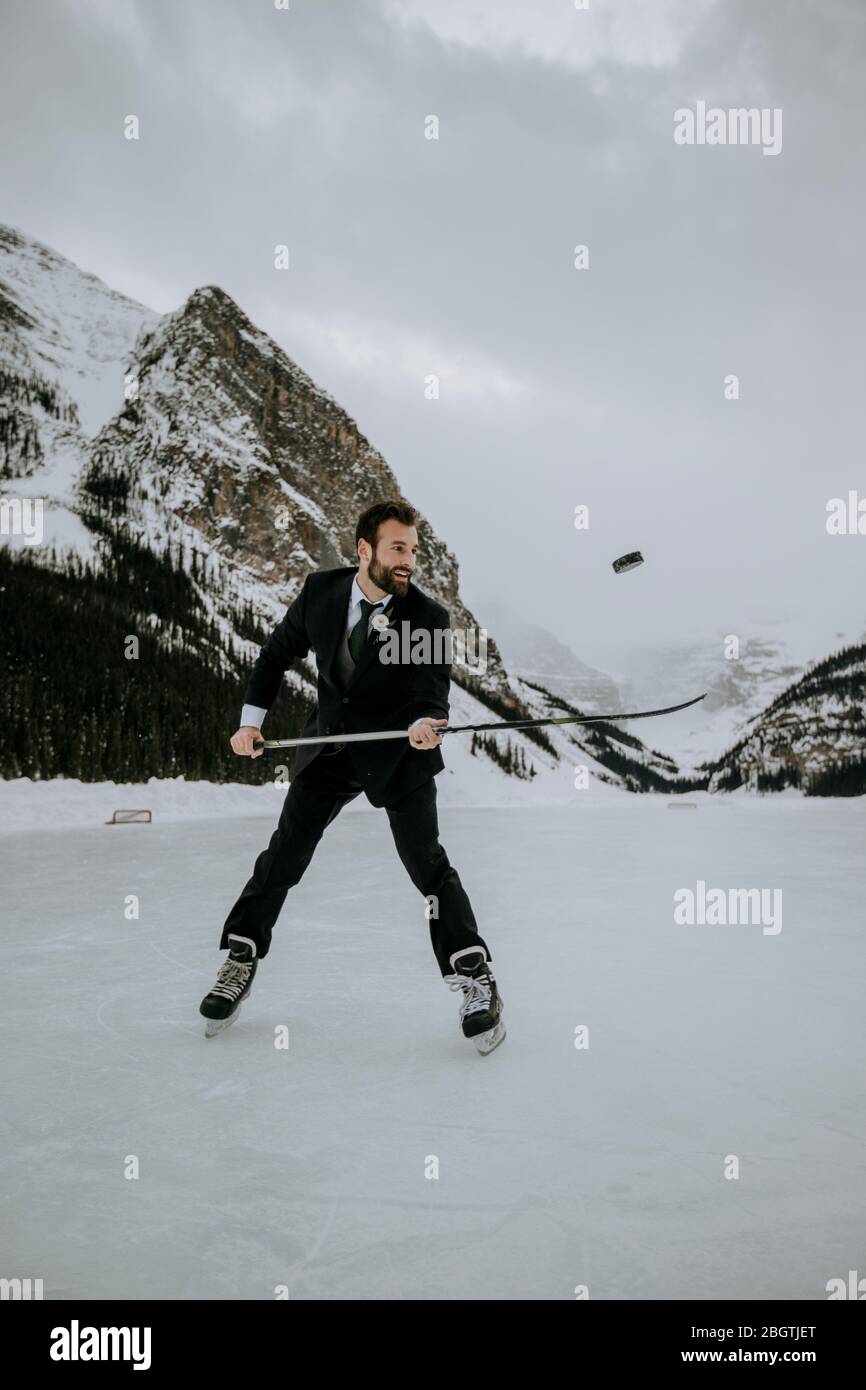 hockey player with suit on juggles puck on frozen lake in mountains Stock Photo