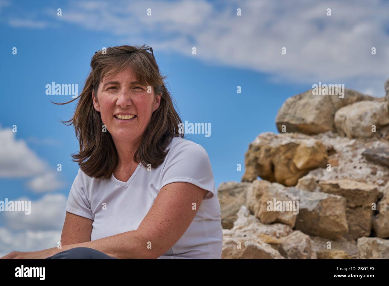 Thoughtful Woman Sitting On Rock Stock Photo