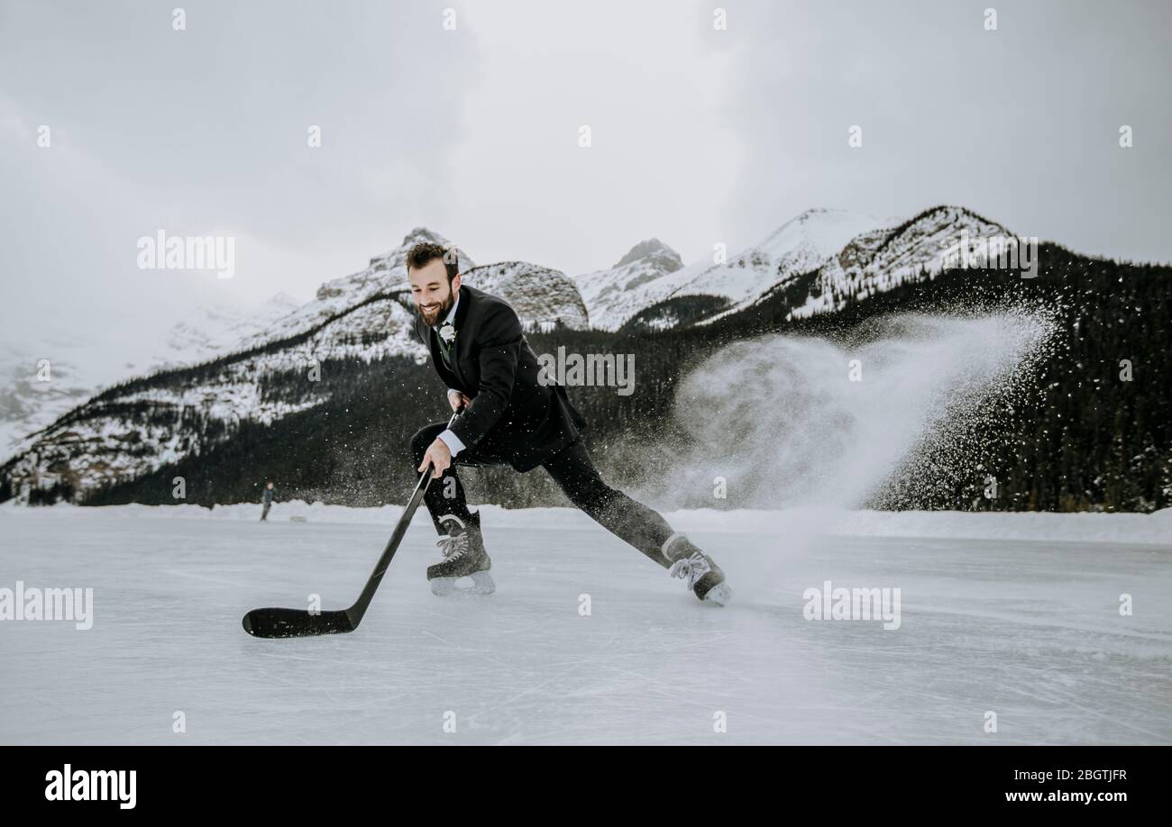 hockey player in suit stops fast kicking up frozen spray on lake Stock Photo