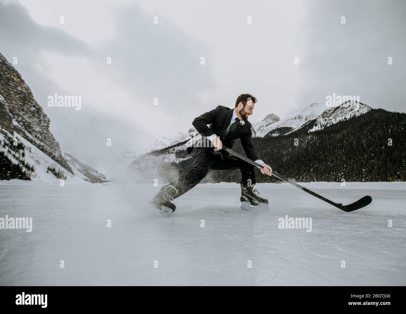 hockey player on frozen lake in suit stops fast and sprays ice Stock Photo