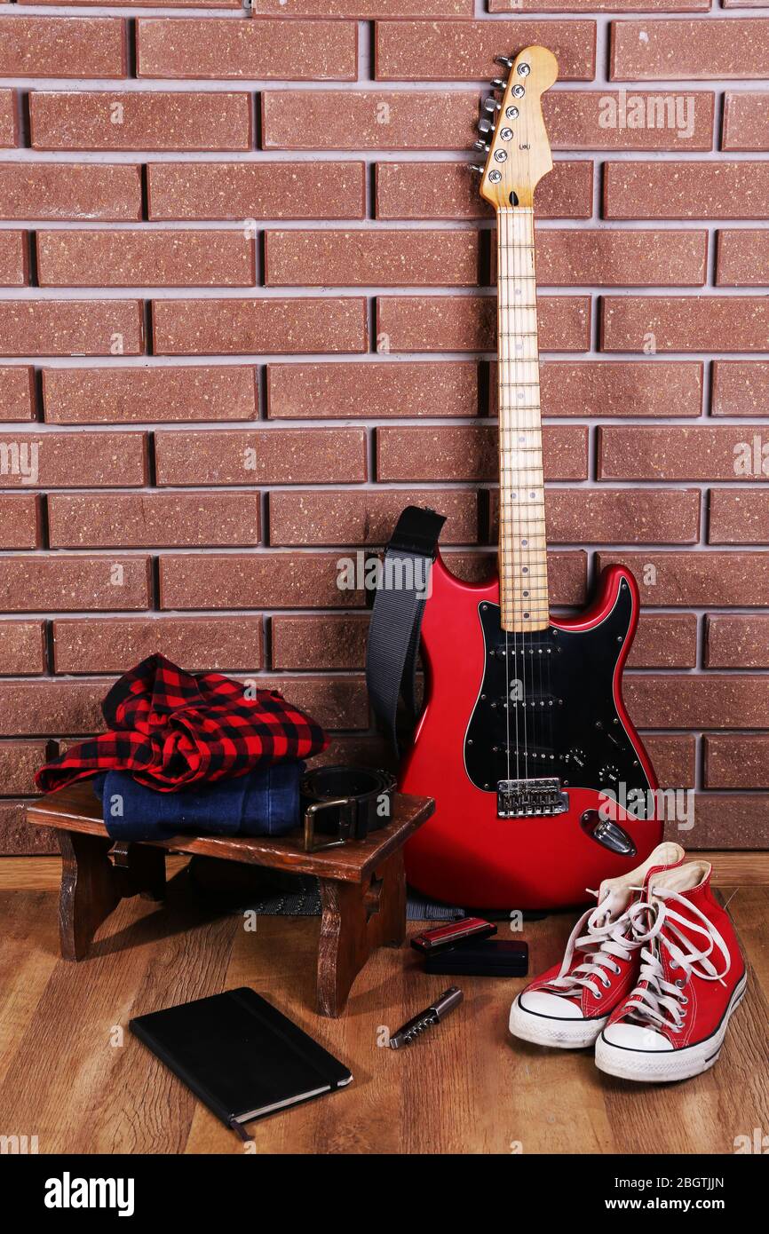 Guitar, trainers and clothes on brick wall background Stock Photo - Alamy