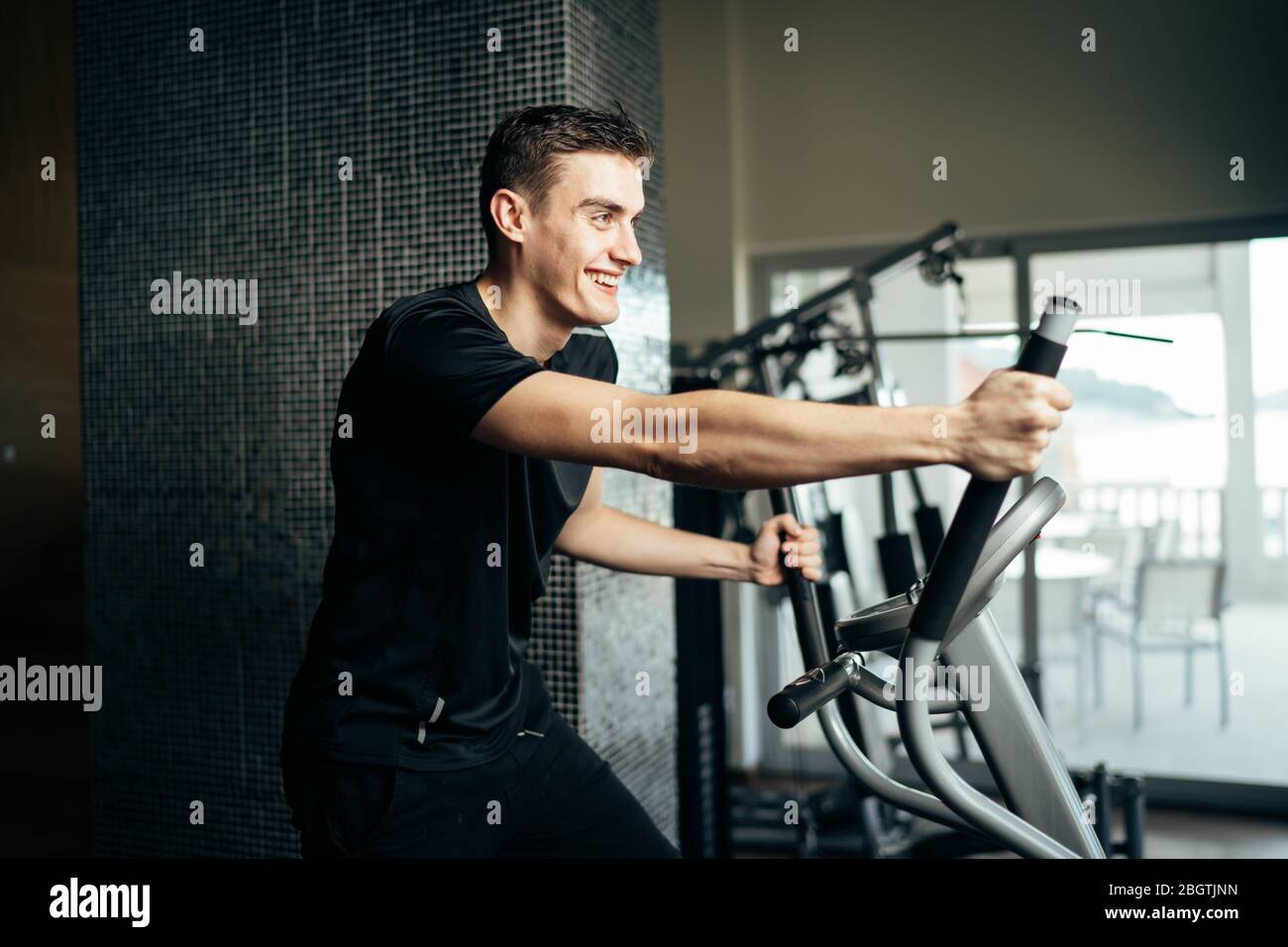 Young man doing fitness exercises on stepper at home gym.Making an effort and training for fit body shape,weight loss.Excess body weight.Home workout. Stock Photo