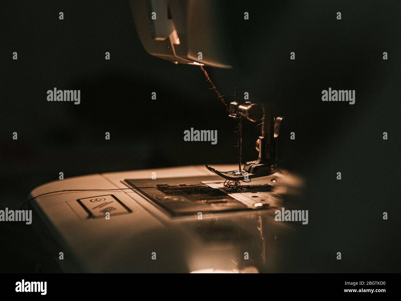 Old sewing machine with black thread scissors and needle, on a old grungy work table. Stock Photo