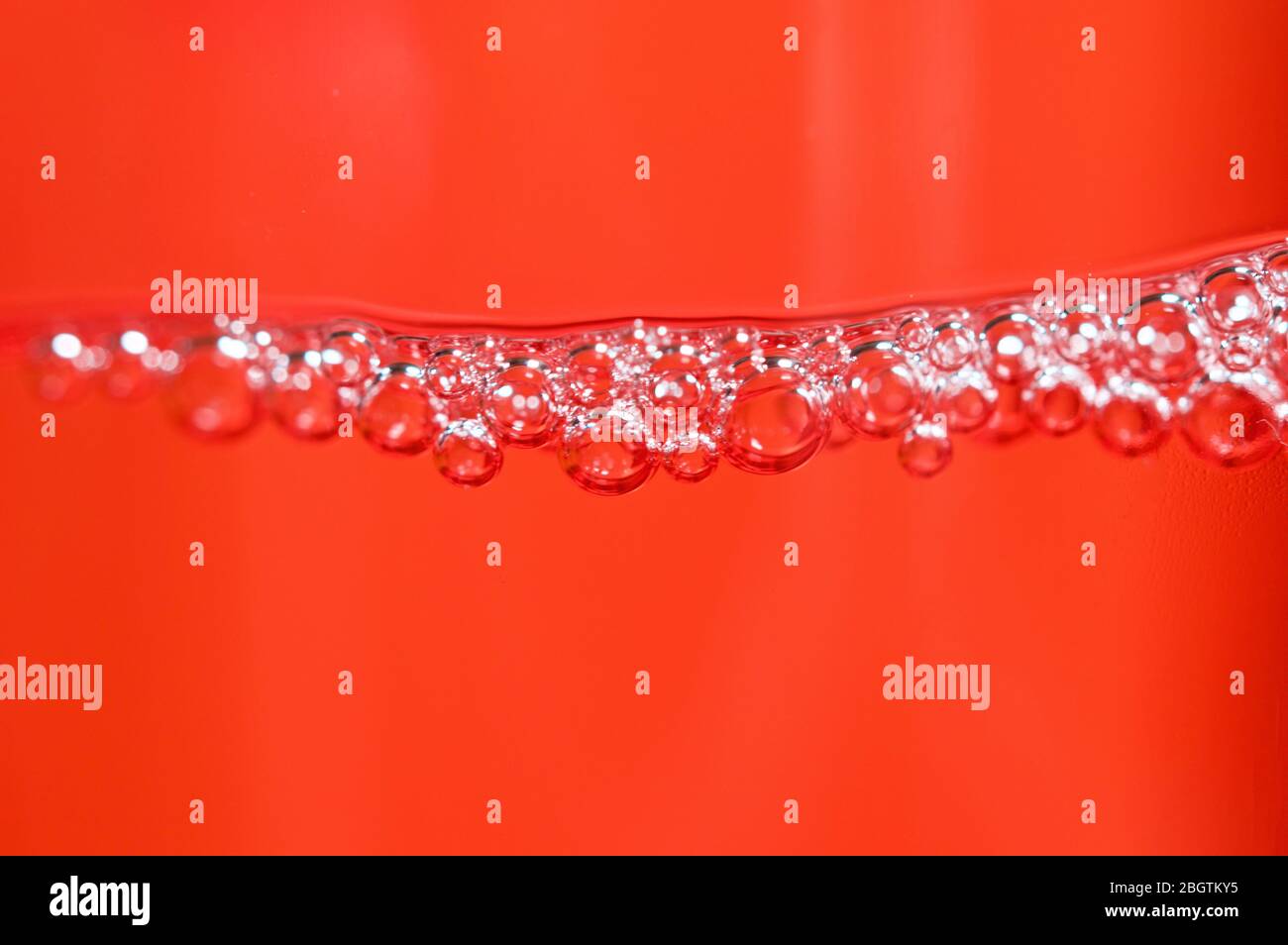 Red detergent bubbles in macro view Stock Photo