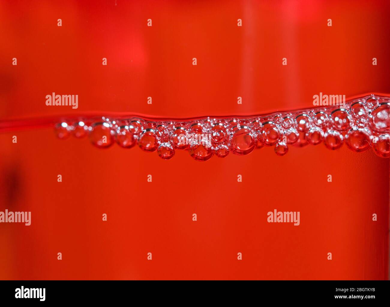 Red detergent bubbles in macro view Stock Photo